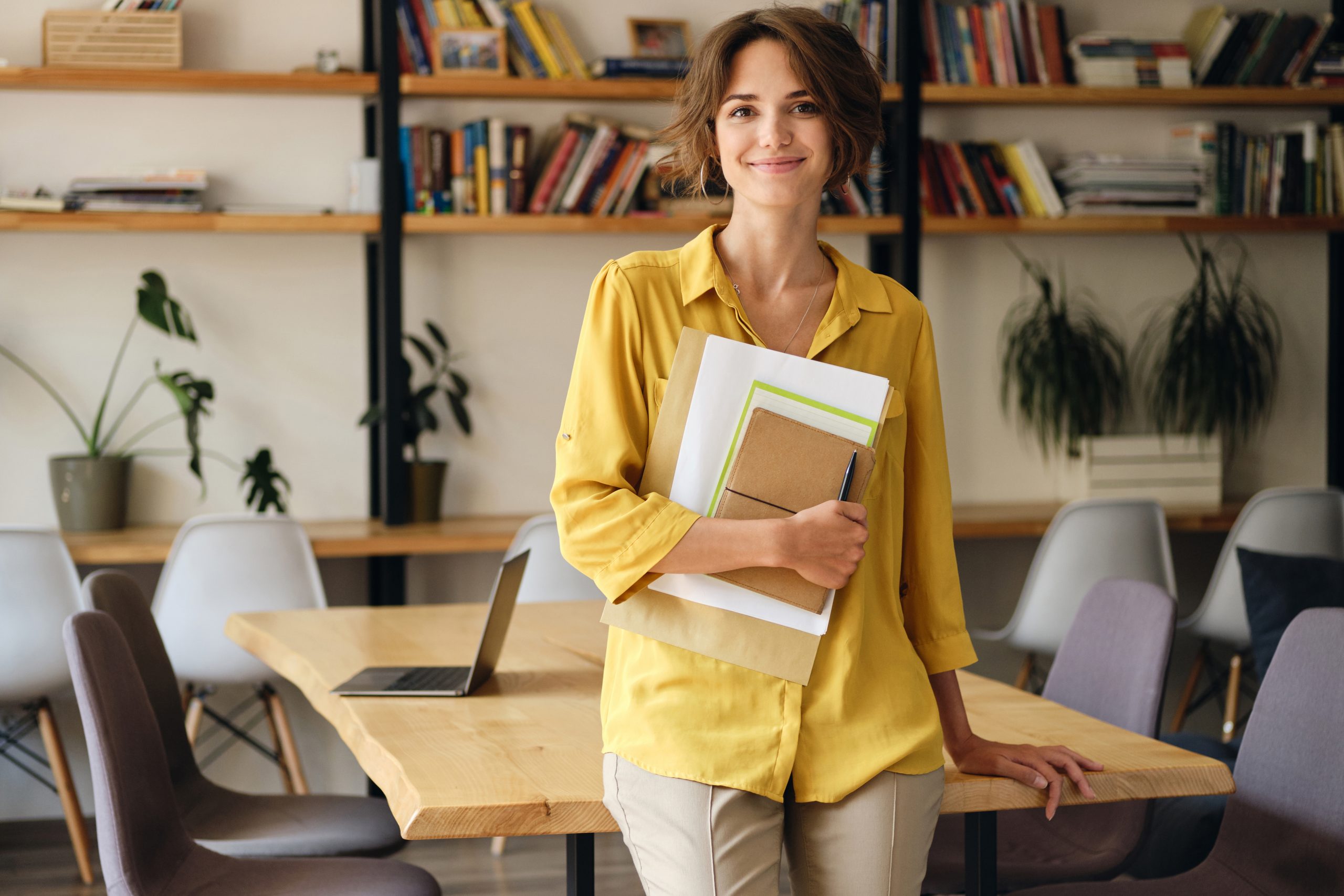 smiling-woman-in-yellow-shirt-with-notepad-and-pap-JKDM9YS-scaled.jpg