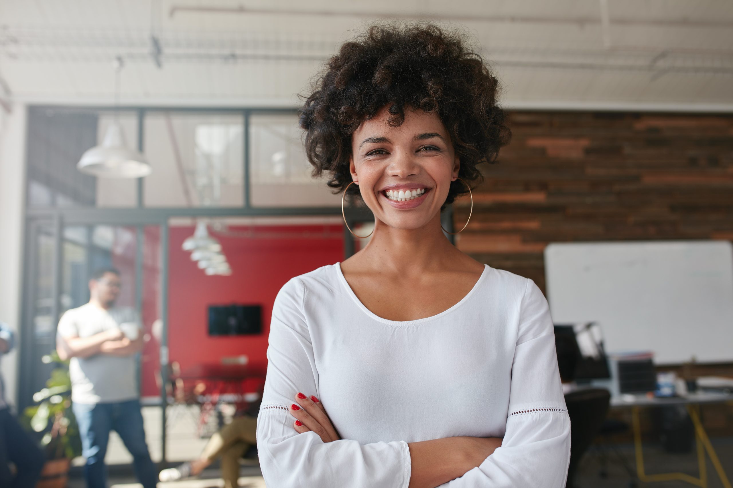 smiling-young-woman-standing-in-creative-office-PHKL7DX-scaled.jpg